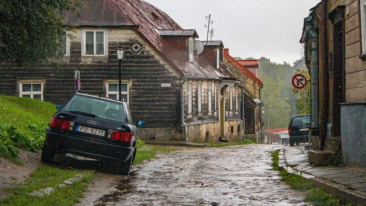 black car parked beside brown brick building during daytime